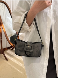 Detail of grey washed denim baguette bag worn on shoulder with vintage buckle