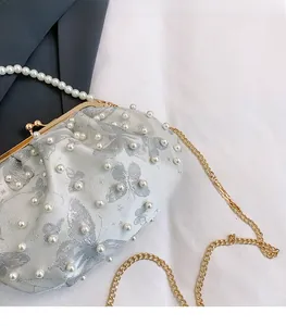 Detail view of pearl clutch bag with silver butterfly print and gold chain strap