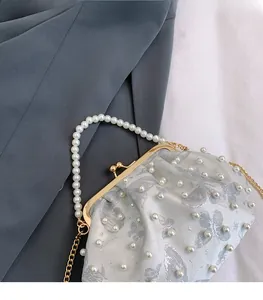 Detail of white satin bag with silver butterfly jacquard, pearls, and gold chain strap
