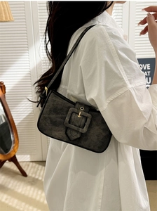 Detail of dark grey denim underarm bag with large decorative square buckle and gold hardware
