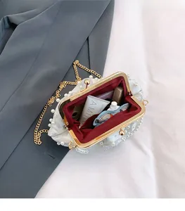 Detail view of pearl-embellished shell bag with spacious interior and gold chain