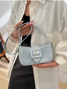 Detail of light blue denim shoulder bag with retro square buckle and premium texture