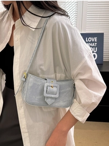 Detail of light blue denim baguette bag featuring a square buckle and gold hardware