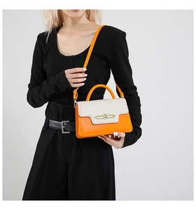 Model wearing orange and beige color block crossbody bag with gold metal hardware lock