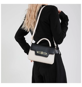 Model wearing a black and white patchwork small square bag with golden twist lock detail