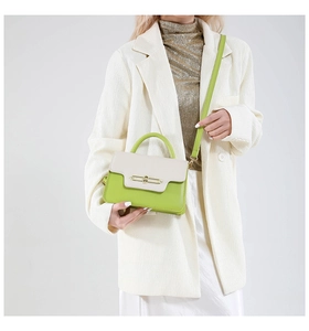 Detail of trendy color-block crossbody bag with green leather and gold buckle