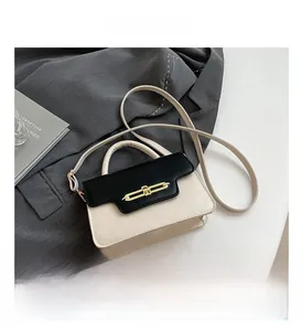 Detail of a contrast color crossbody bag with gold buckle on a grey suit background