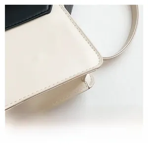 Macro view of beige leather stitching and black edge finishing on square handbag