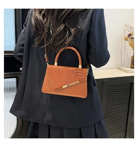 Borsa a mano marrone con stampa coccodrillo indossata da una modella con blazer blu