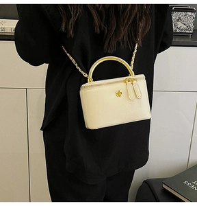 Detail of cream glossy mini crossbody bag featuring golden handle and floral metal buckle