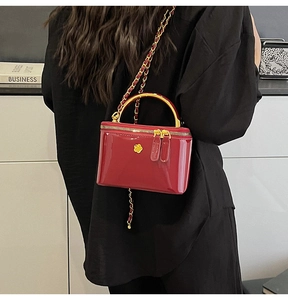 Detail of red patent leather mini bag with gold floral logo and chain strap