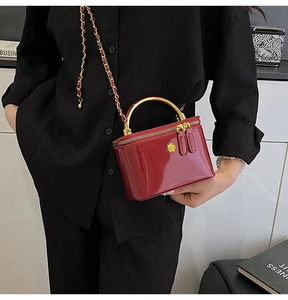Close-up of wine red glossy mini bag with gold camellia detail and chain strap