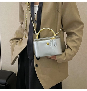 Detail of silver mirror leather bag with gold floral logo and chain strap