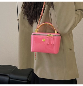 Detailed view of the bright pink glossy box bag with gold handle and woven chain strap