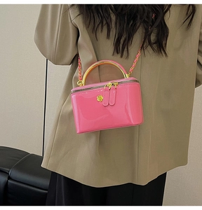 Detail of pink glossy patent leather vanity bag with gold handle and chain strap