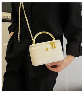 Detail of white snakeskin texture mini bag with gold camellia logo and metal handle