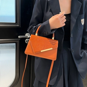 Borsa a mano arancione stampa coccodrillo con barra in metallo dorato indossata da modella