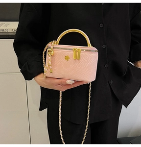 Detail of pink snakeskin pattern bag with gold flower ornament and metal handle