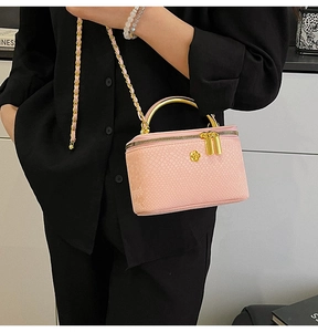 Detail of pink faux-snakeskin vanity case bag with gold metal handle and chain strap