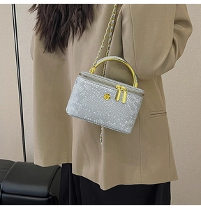 Detail of grey snake print vanity bag with golden flower accent and chain strap