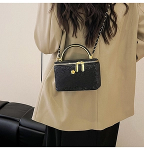 Detail of snake skin texture vanity box bag with gold floral zipper and chain strap