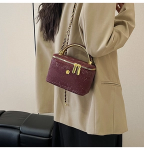 Detail of burgundy snakeskin chain bag with gold flower crest and metallic handle