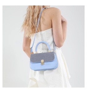 Side view of model wearing a light blue crossbody square bag with a textured grey flap