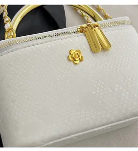 Detailed macro view of white snakeskin texture and golden camellia metal ornament on the bag