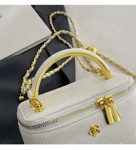Detail of white snakeskin texture with gold curved handle and camellia logo on the bag