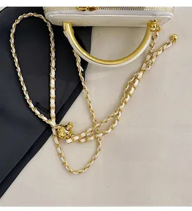 Close-up of white leather bag with gold chain strap and adjustable golden metal ball