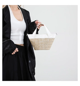 Detail of woven straw and white leather patchwork bucket bag shown on a female model