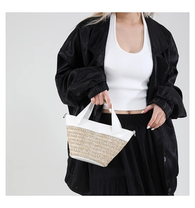 Detailed close-up of woven straw and white leather patchwork on a stylish summer bucket bag