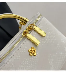 Macro shot of snake-embossed white leather texture and gold-tone floral hardware detailing