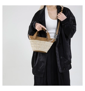 Detail of woven straw texture and premium brown leather trim on a summer bucket bag