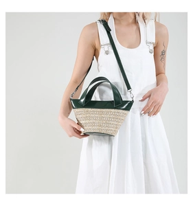 Detail of dark green leather stitching and woven straw bucket bag with adjustable strap