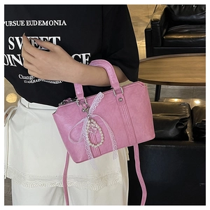 Detailed view of pink crossbody bag with lace pearl charm accessory and dual handles