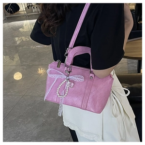 Detailed close-up of pink pillow bag with lace bow, pearl charm and pleated leather texture