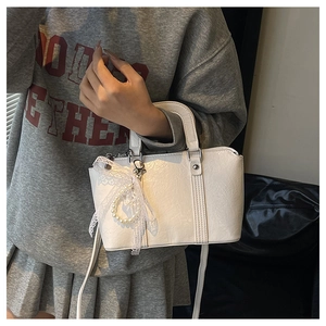 Detailed view of white ribbon pillow bag with lace trim and elegant pearl ring charm