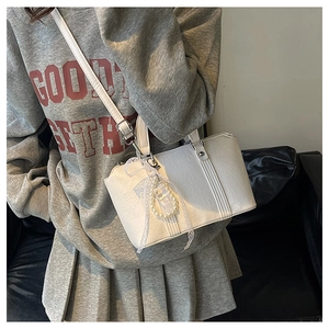 French style white leather pillow bag with pearl bow pendant worn by a model