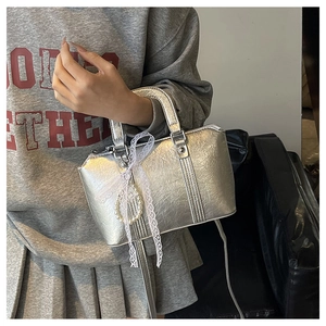 Detail of silver metallic handbag featuring lace bow and pearl charm accessories