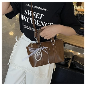 Detail of dark brown leather handbag with lace bow and pearl chain charm