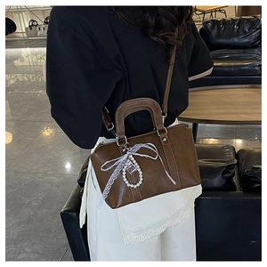 Detail of brown vintage crossbody bag with lace bow and pearl handle decoration