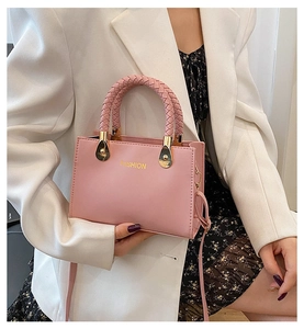 Detailansicht der rosa Handtasche mit geflochtenem Griff und goldener Fashion-Schrift