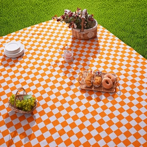Classic orange and white checkered picnic mat on green grass for outdoor camping