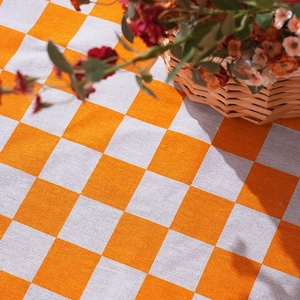 Classic orange and white checkered picnic mat with woven texture and a basket