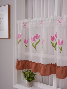 Détail de tulipes brodées et bord à volants marron sur rideau brise-bise en voile blanc