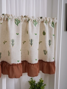 Detail of beige linen cafe curtain with cactus embroidery and brown ruffled hem