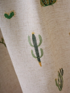 Macro shot of colorful cactus embroidery on natural linen cabinet curtain fabric