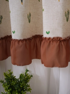 Detail of linen cabinet curtain featuring cactus embroidery and brown chiffon ruffle edge
