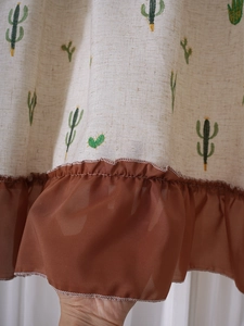 Detailed close-up of pastoral linen fabric with cactus embroidery and chiffon ruffles